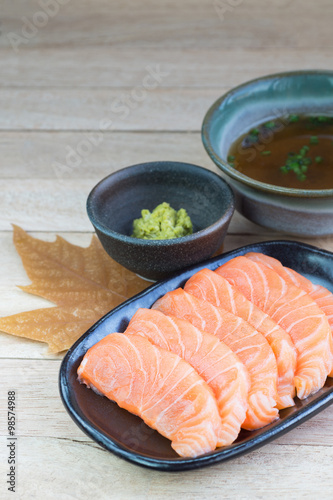 Sliced raw salmon on black plate with wood background