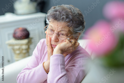 Forlorn elderly lady sitting alone photo