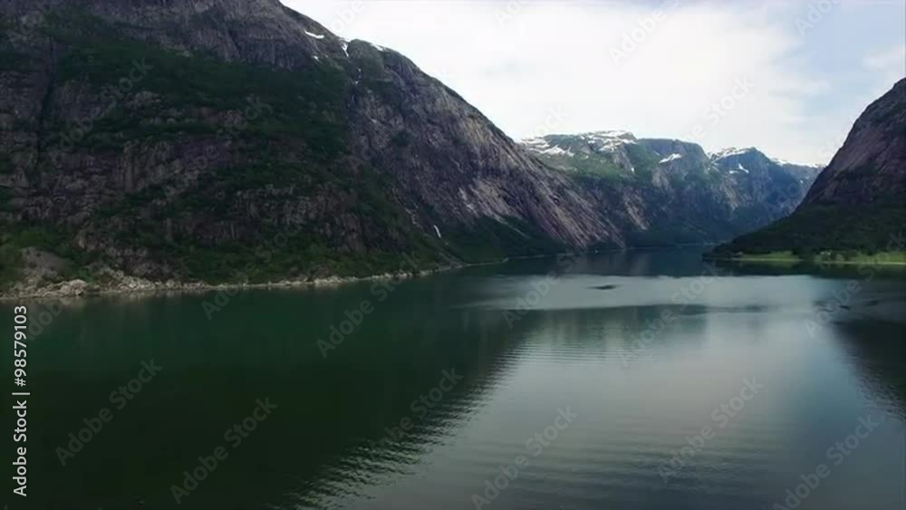 Slow flight above Hardanger fjord in Norway with tall cliffs towering above. Aerial 4k Ultra HD. Slow flight above Hardanger fjord in Norway with tall cliffs towering above. Aerial 4k Ultra HD.