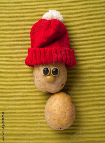 Happy Christmas potato in santa hat on yellow background