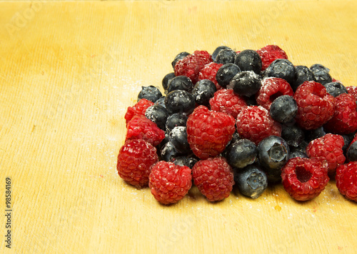 A handful of frosted highbush blueberries and raspberries on old photo