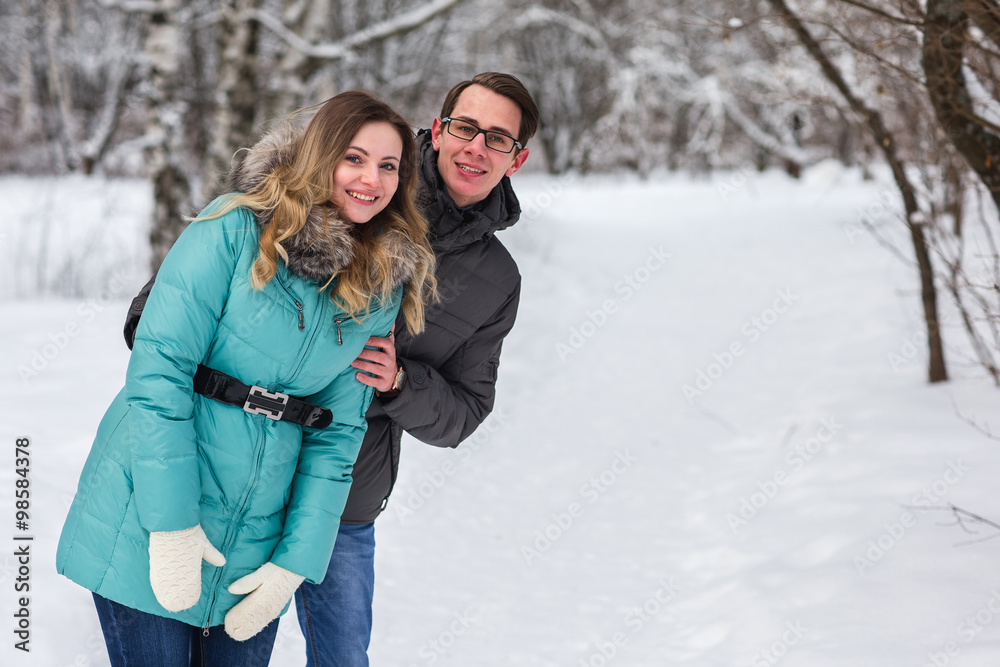 Young beautiful couple walking in winter forest