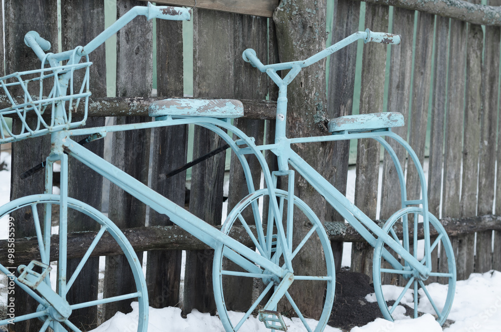 vintage bicycle rests on a wooden fence