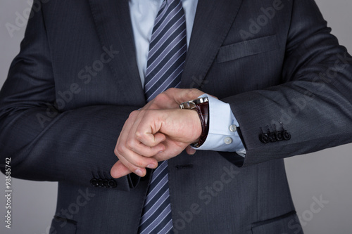 Young business man looking at his wristwatch checking the time