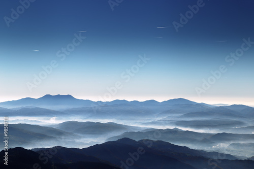 Avion tracks in blue sky above mountains photo