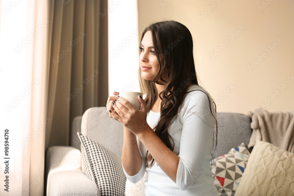 Beautiful woman relaxing on sofa in the room with cup of coffee Beautiful woman relaxing on sofa in the room with cup of coffee