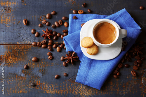 Cup of coffee with spices on wooden table background