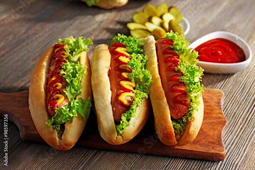 Delicious hot-dogs on wooden chopping board