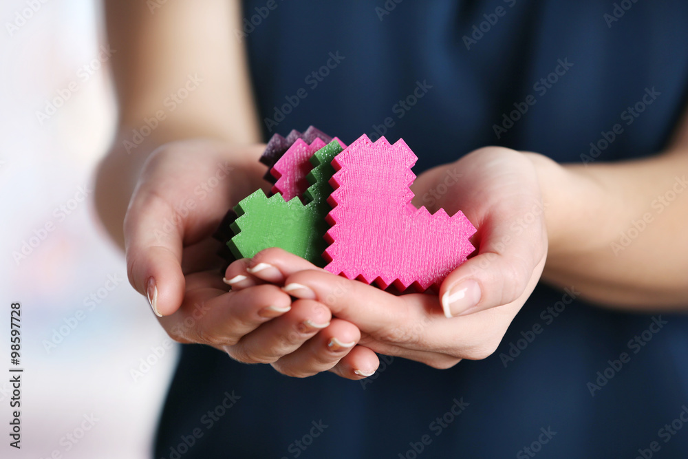 Closeup of plastic puzzle hearts in female hands Closeup of plastic puzzle hearts in female hands