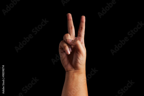 human hand forming a victory sign over a black color background
