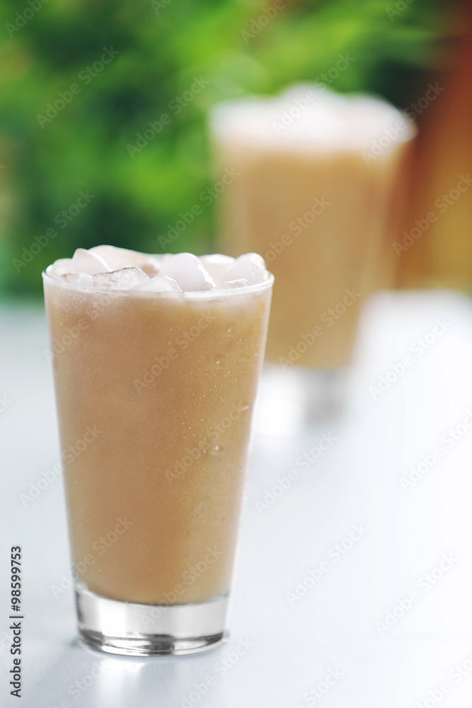 Cups of ice coffee on light blurred background