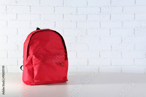 фотографія School backpack on wooden table, on wall background