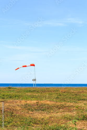 a wind force (windsock) against the dark sea and blue sky