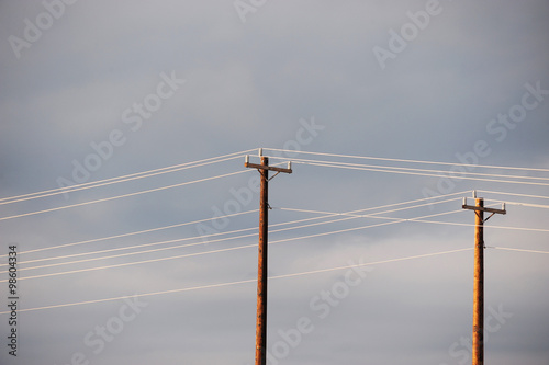 фотографія power poles against cloudy sky