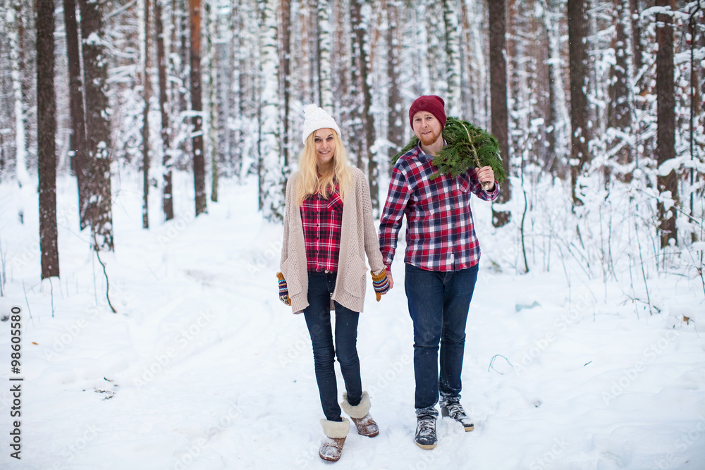 young couple in a plaid shirt with fir twigs walk in the winter woods