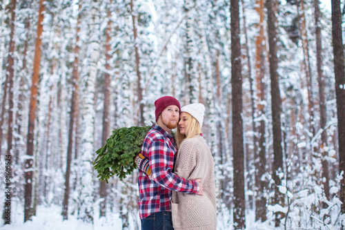 young couple in a plaid shirt with fir twigs walk in the winter woods