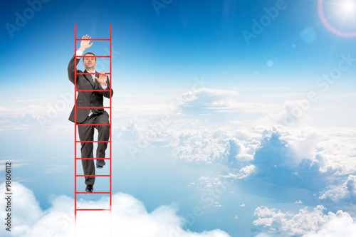 Valokuva Businessman climbing ladder in sky
