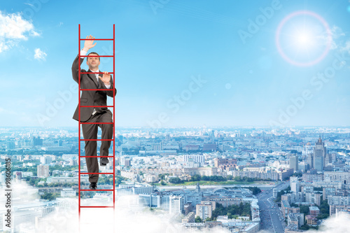 Billede på lærred Businessman climbing red  ladder in sky