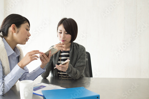Two women are talking to see the smartphone