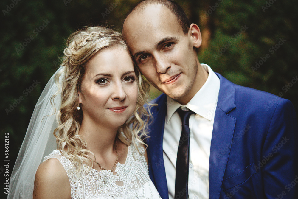 happy blonde bride and elegant groom on a background of beautiful sunny trees in a forest, close up
