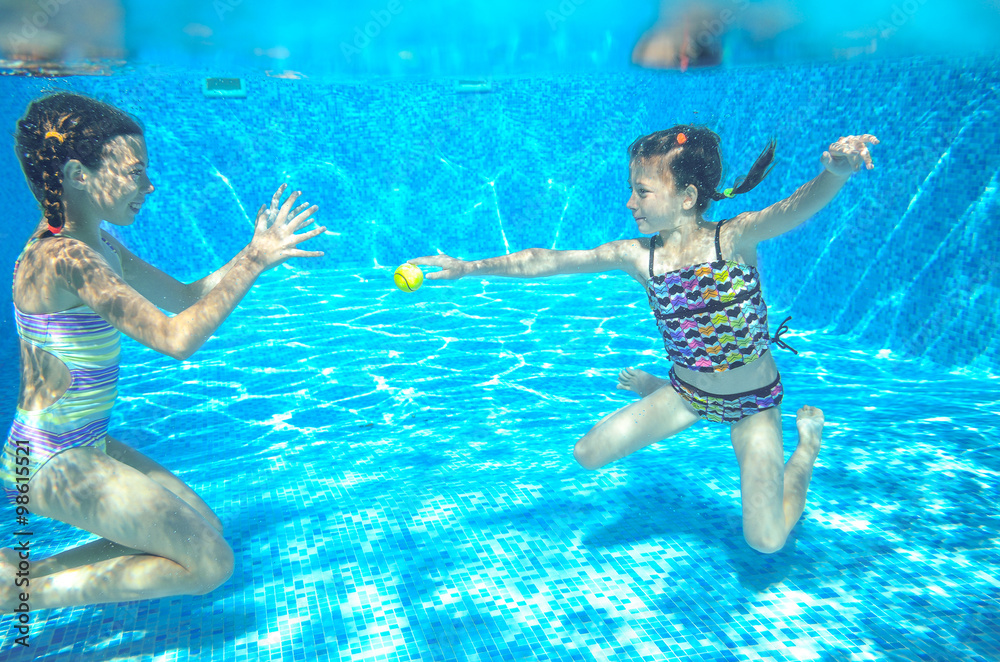 Children swim in pool or sea underwater, happy active girls have fun under water
