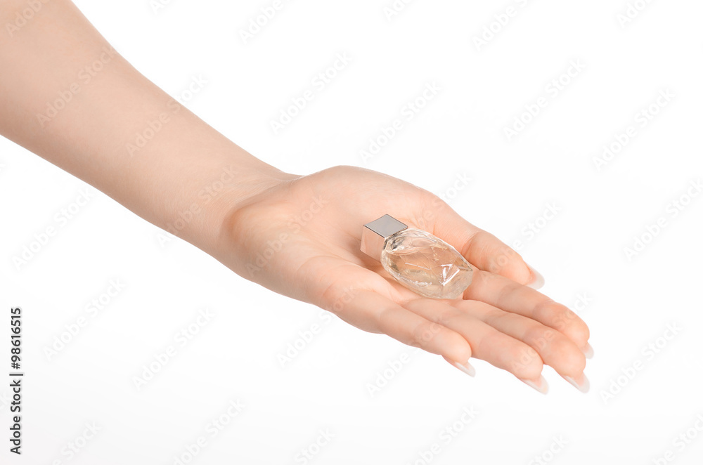 Perfume and body care theme: beautiful female hand holding a small transparent bottle of perfume on a white background isolated