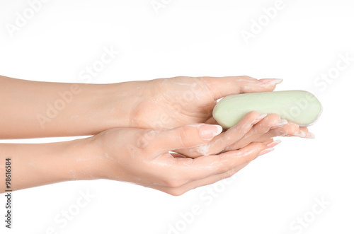 Hygiene and health care topic: a woman's hand holding a green bar of soap isolated on white background in studio