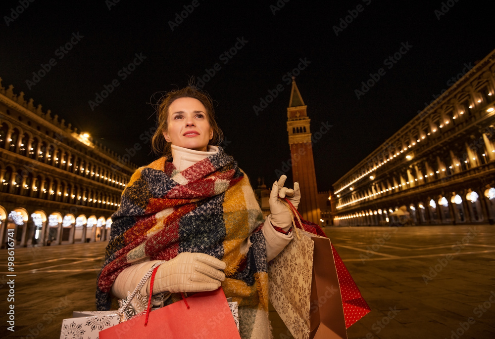 Modern woman with shopping bags on Piazza San Marco in evening