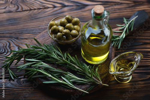 Closeup of extra virgin olive oil with fresh rosemary and olives