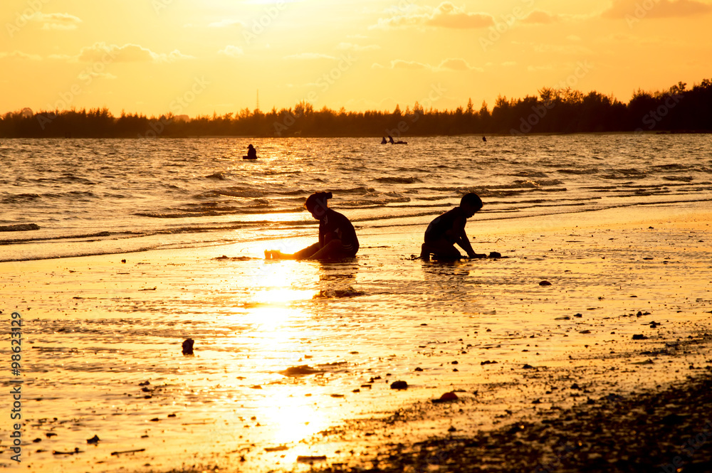 Silhouette of children playing on the beach at sunset