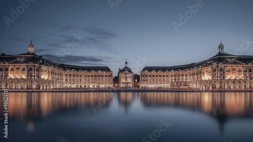 Illuminated neoclassical buildings reflected in the Garonne river, Place de la Bourse, Bordeaux, Gironde, France