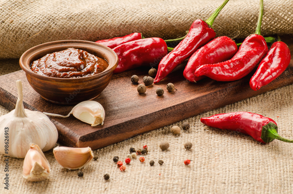 Red sauce, spices and pepper on a kitchen board