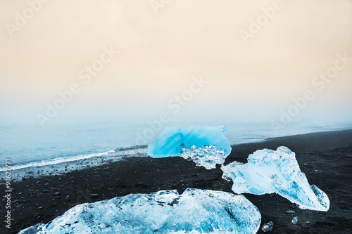 Blue icebergs on the beach with black volcanic sand.