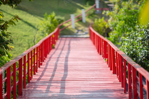 Red wooden bridge over the river in the park.