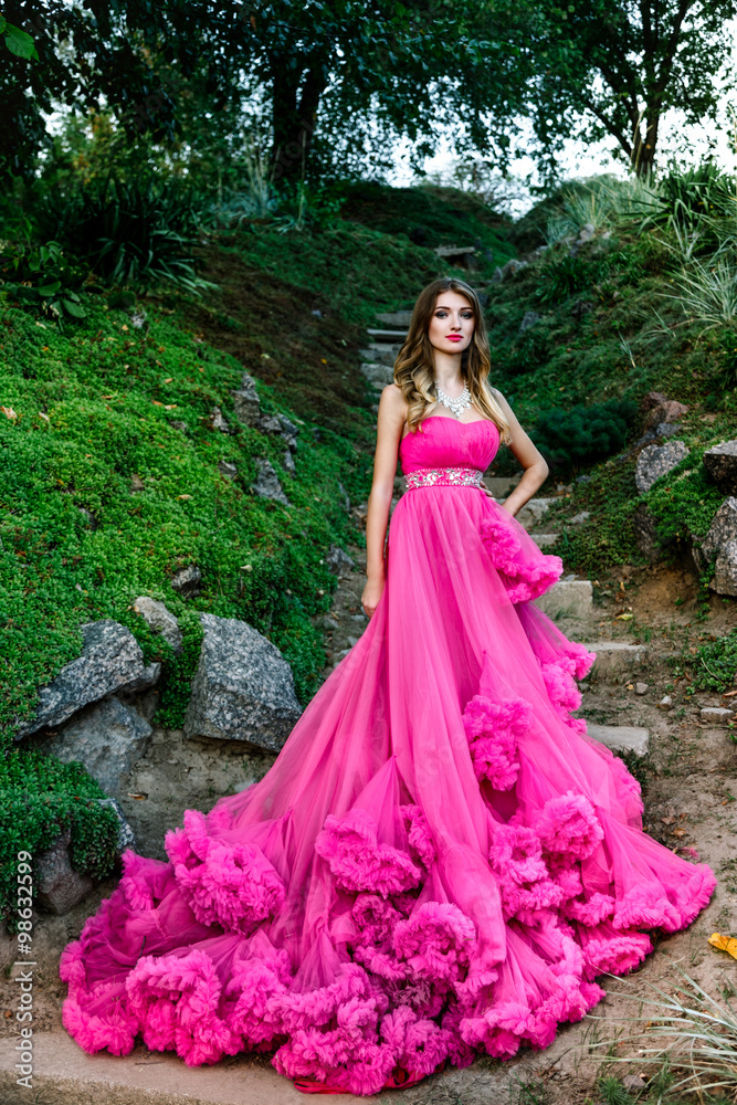 Beautiful woman in gorgeous pink dress outdoors . Full length Portrait.