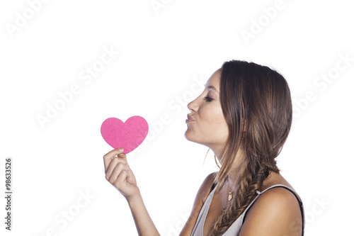 Isolated happy young caucasian woman holding a heart and giving a kiss