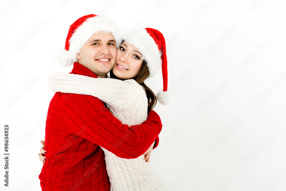 Happy embracing couple in Christmas caps Happy embracing couple in Christmas caps