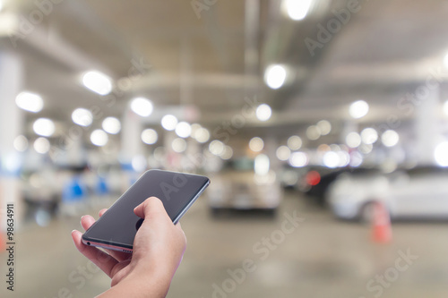 Mobile hold in hand with blur cars parking