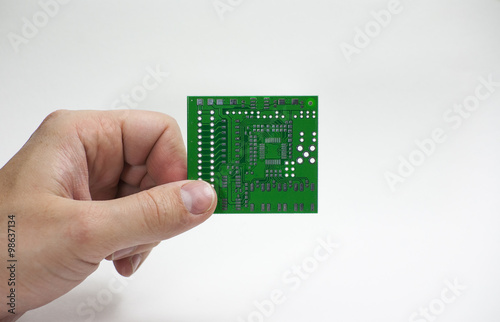 Human hand holding a printed circuit board in fingers