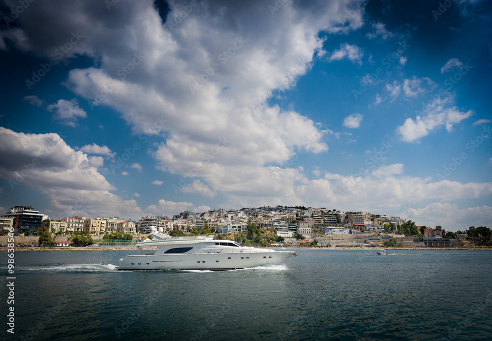 Fast white luxury yacht under big clouds somewhere at Piraeus port.Greece