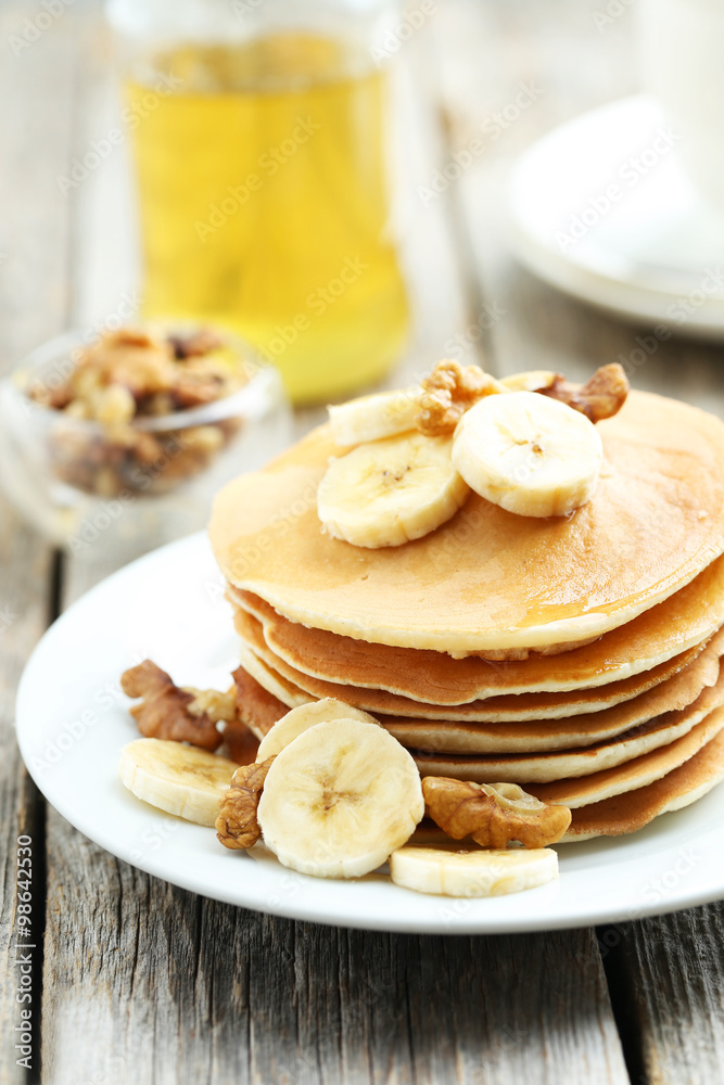 Tasty pancakes with banana and walnut on grey wooden background