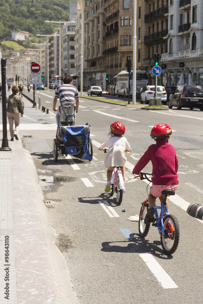 A man with his children on a walk/The man with the kids on a bike ride around the city. Spain. San Sebastian. June 2014