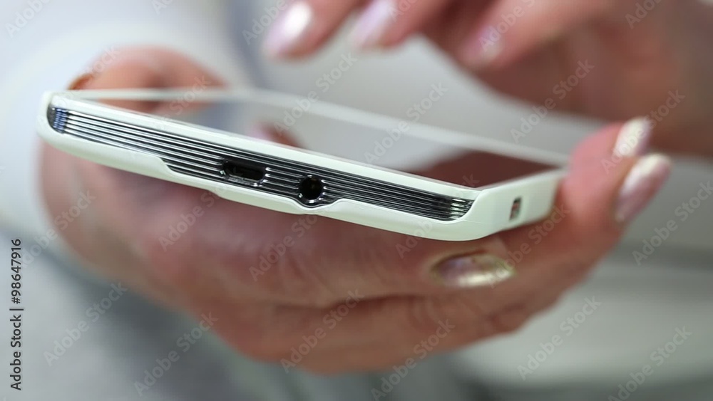 Closeup of woman hands with white smartphone. Woman with mobile phone. Woman uses white smartphone. Senior woman looks and flips through the photos in her smartphone Closeup of woman hands with white smartphone. Woman with mobile phone. Woman uses white smartphone. Senior woman looks and flips through the photos in her smartphone