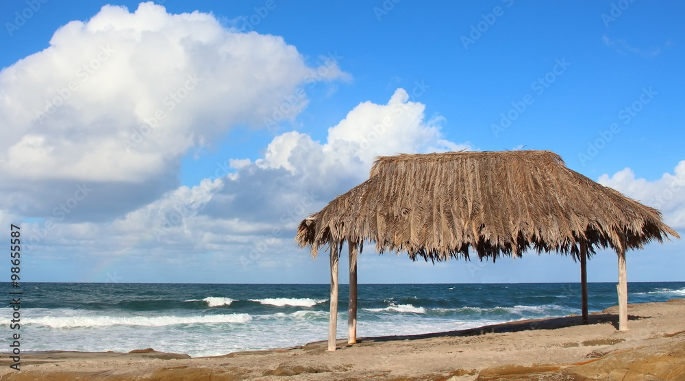 Hut on Beach – Old thatched hut on the beach on a bright blue day in the summer