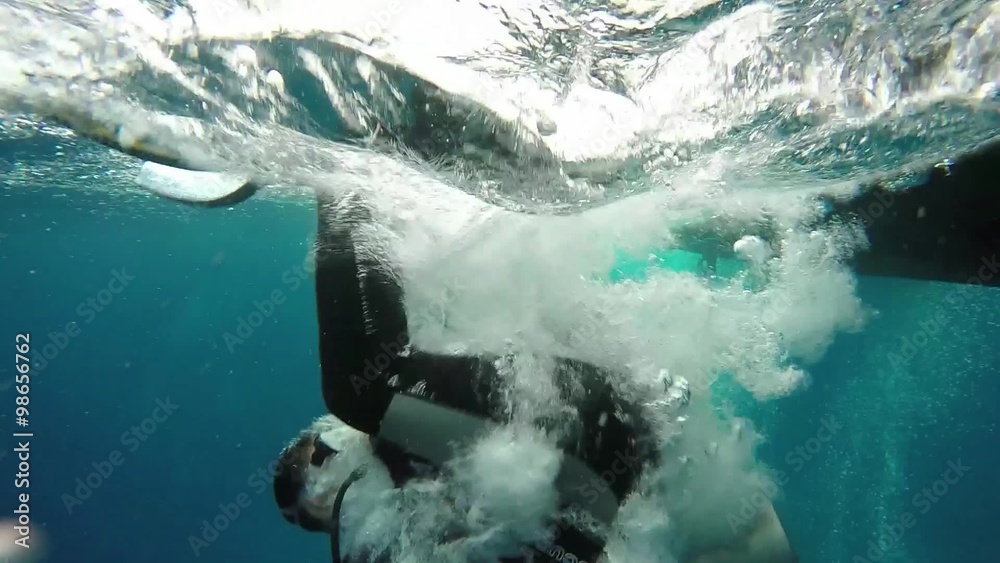 Scuba diver slow motion backwards roll entry off boat into ocean, at