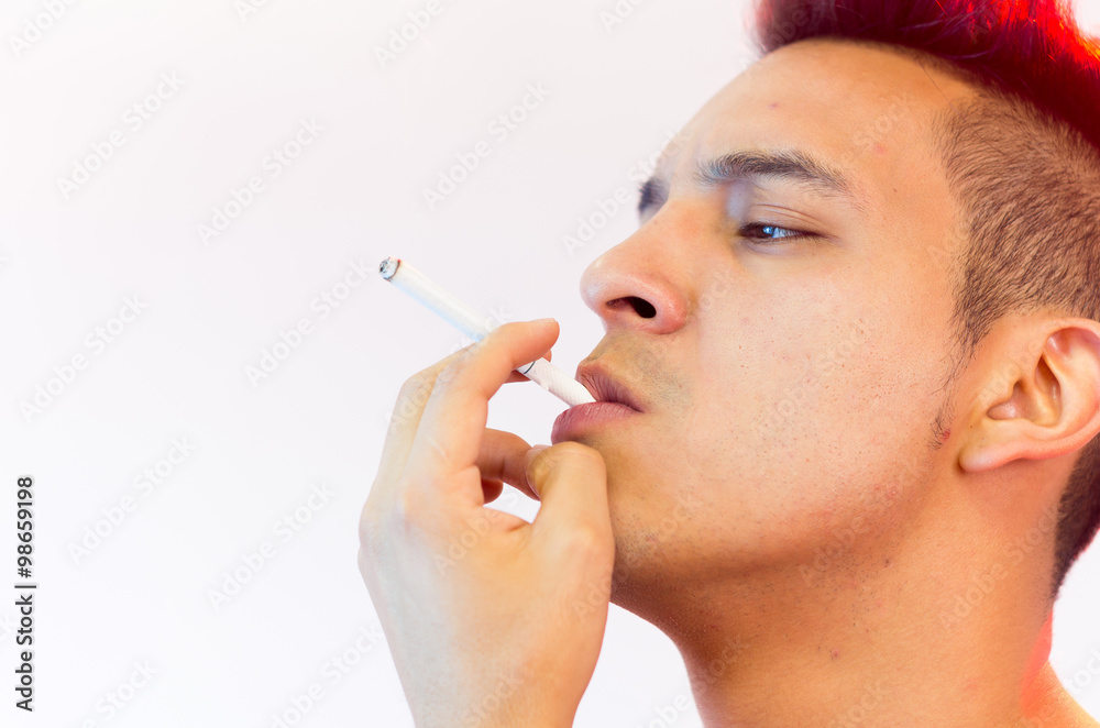 Hispanic male headshot posing with serious facial expression and smoking a cigarette Hispanic male headshot posing with serious facial expression and smoking a cigarette
