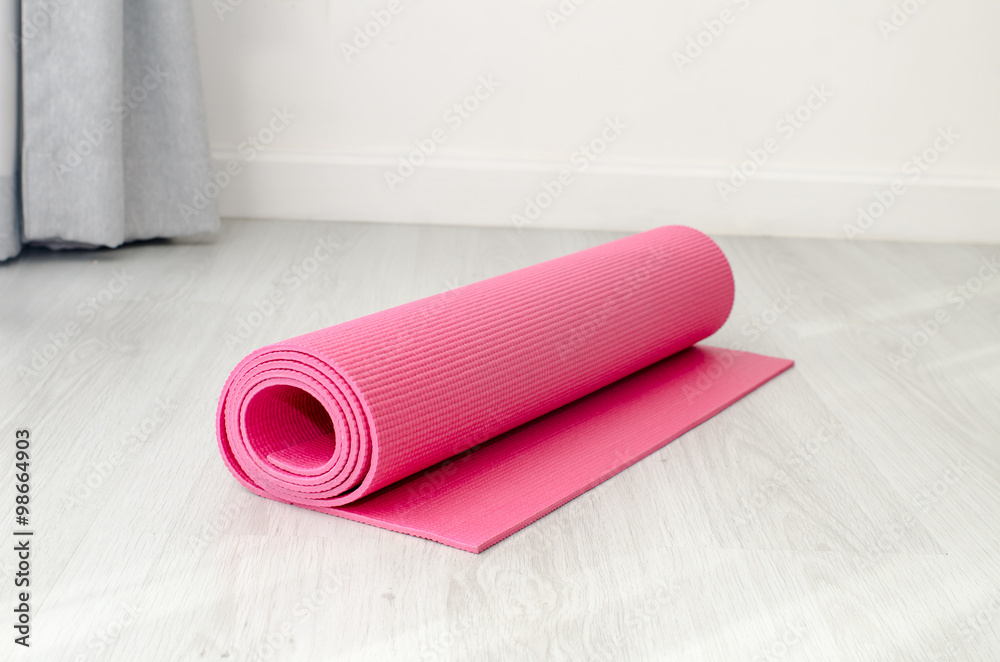 Obraz premium Pink yoga mat on gray floor at home. Health concept.