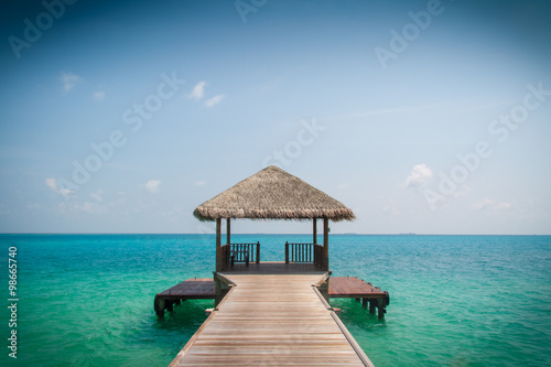 Wooden pier leading to cyan Indian Ocean and blue sky