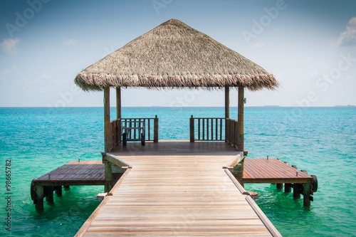 Wooden pier leading to cyan Indian Ocean and blue sky