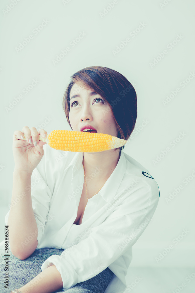 Asian girl eating yellow corn at home. Asian girl eating yellow corn at home.